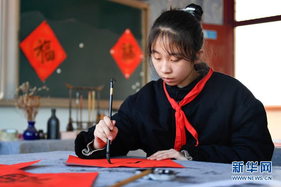 时间开展迎新春民俗活动,学生在老师的带领下写"福"字,剪窗花,画年画