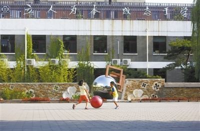 8月15日，清华附小，两名学生在校园里玩耍，背后的楼上悬挂着校训“立人为本，成志于学”。
